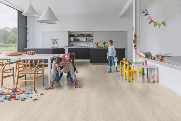 Gezin speelt op een lichte eikenhouten vloer in een open woonkeuken